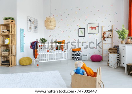 Rattan lamp above white bed with colorful blanket in child's bedroom interior with wooden shelf