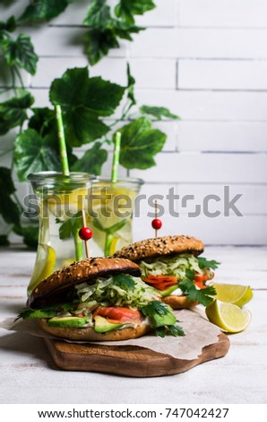 Burger with salted salmon and vegetables on wooden background. Selective focus.