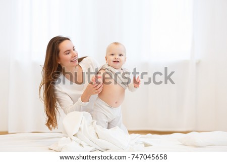 happy loving family. Young mother playing with her baby in the white bedroom.