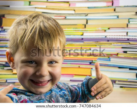 The little boy spread his fingers against the background of a large number of colorful books.