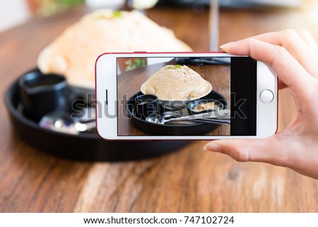Woman taking a picture of a Injeolmi Bingsu (Bingsoo) in disk on table 