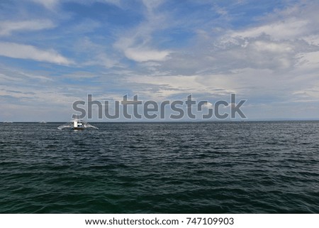 Small boat floating in the sea. Photo taken on a warm, bright afternoon during an island hopping activity in the tropical country of the Philippines.