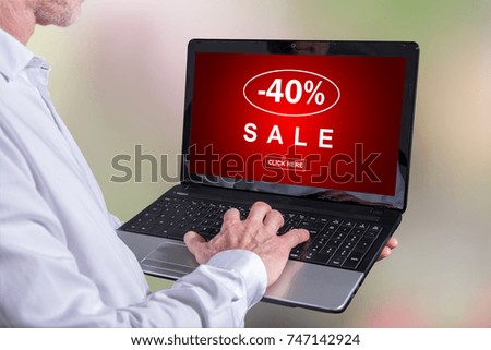 Man using a laptop with sale concept on the screen