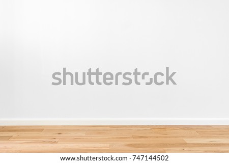 White painted stucco wall and natural wooden ash-tree 3-band parquet board hardwood floor. Flooring in scandinavian style of empty interior with wide white baseboards. Light brown, biscuit color Royalty-Free Stock Photo #747144502