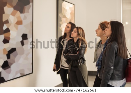Four girl friends looking at modern painting in art gallery. Abstract painting Royalty-Free Stock Photo #747162661