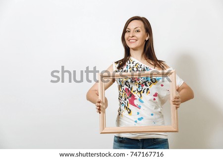 The portrait of a happy smiling brown-haired woman standing and holding empty wooden frame on the white background.
