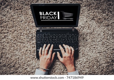 Black Friday advertisement in a laptop screen while woman uses it to buy by internet. Top view.