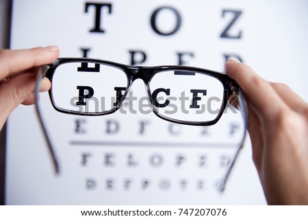Glasses  in the hands on the background of the table for vision Royalty-Free Stock Photo #747207076