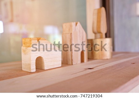 Small wooden house and tree models on table and glass wall as background