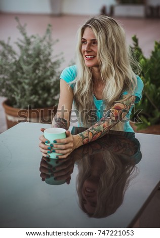 Portrait of a beautiful blonde with expressive eyes. Holding a mug of coffee. The concept of turquoise color. Modern woman
