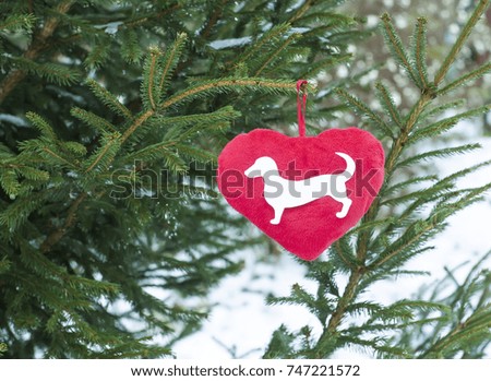 Paper dog figure on red decorative plush heart hanging on fir tree green branches. 2018 New Year greeting card. 