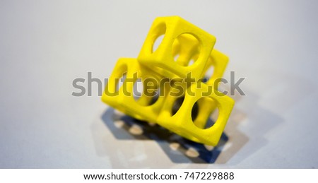 Abstract object of a yellow color printed on a 3d printer on a white table. Fused deposition modeling, FDM. Progressive modern additive technology. Concept of 4.0 industrial revolution