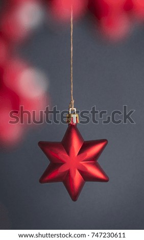 Christmas decoration star hanging in front of a gray neutral background. Red star decorative Christmas ornament. Focused. Copy space.