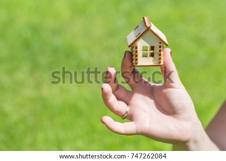 Female hand holding small wooden house. Household concept