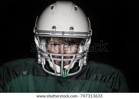 Low key harsh flash image of a boy in a football uniform