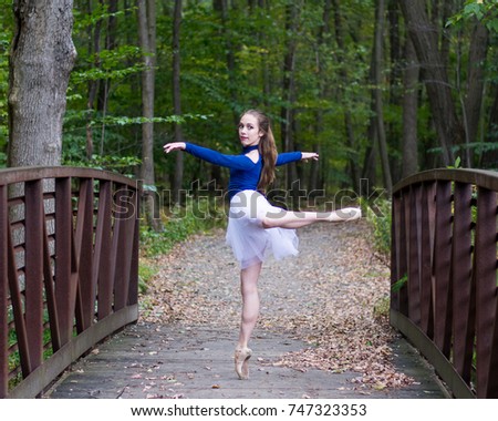 Young teenage dancer on pointe dancing in a wooded forest.