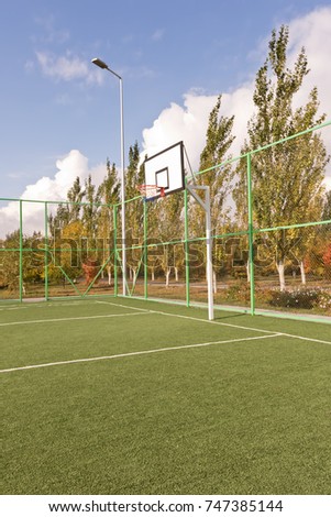 Sports basketball court fenced with mesh and fence at the base of rest surrounded by autumn trees