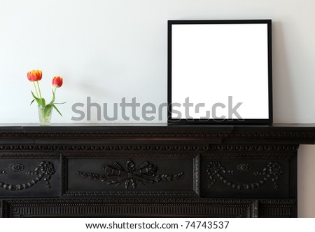 A wooden picture frame on a cast iron mantle piece.