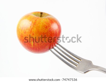 an apple being held up on a fork isolated on a white background