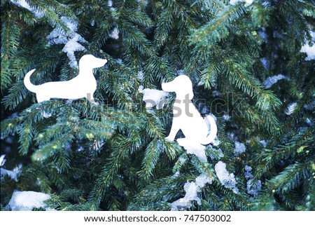 New Year greeting card with paper dog figures on fir tree green branches with snow.