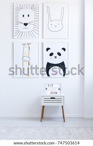 Black and white drawings on wall above cabinet in white autistic kid's room