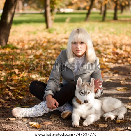 Girl with a dog, a beautiful husky puppy in an autumn park