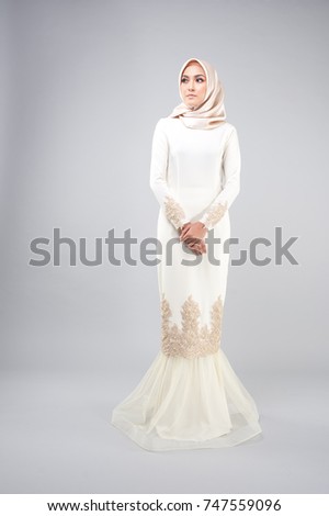 Portraiture of beautiful young Muslim girl wearing Hijab and Dress known as Baju Kurung,Malaysian dress for dinner event,festival and Aidilfitri Feast.Studio shot with grey background.