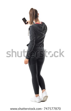 Back view of young sporty fit woman taking photo with smartphone. Full body length portrait isolated on white background. 