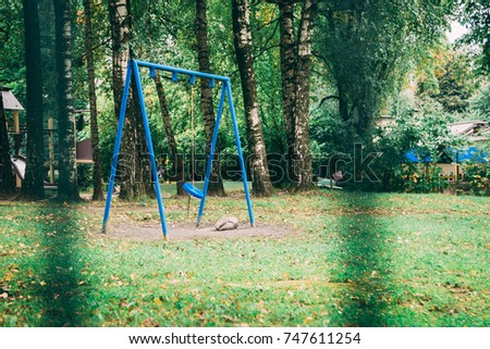 blue swing on a playground in a green park without children