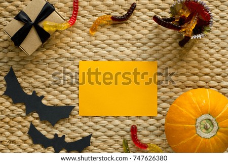 Halloween holiday background with pumpkin, worm candy, ghost, bat. View from above. Nice for mockup.
