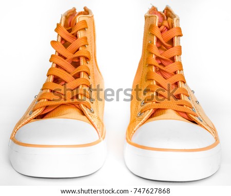 top view to orange new sneakers with white foot and wide open shoelaces on white. modern stylish sneakers isolated on white background. new high keds for woman or man stay strong