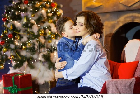 Mother and son tenderly embrace each other in front of Christmas tree