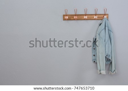 Denim jacket hanging on hook against wall Royalty-Free Stock Photo #747653710