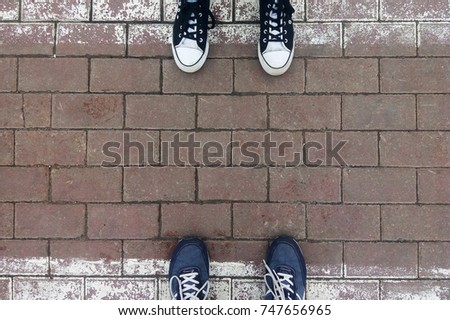 Legs in sneakers on a pedestrian crossing (zebra) against each other