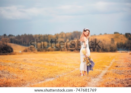 Beautiful girl with a bouquet of blue flowers on nature in autumn
