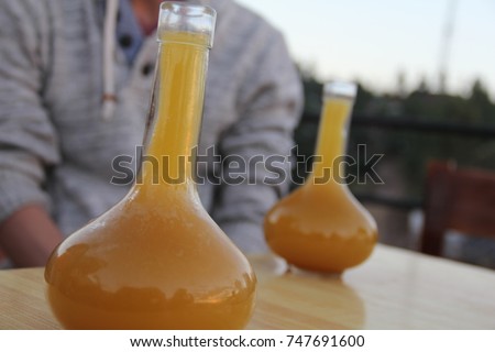 Two glasses of Ethiopian "tej", a mead or honey wine, in a rounded vase-shaped container called a "berele," which looks like a Florence flask. Royalty-Free Stock Photo #747691600