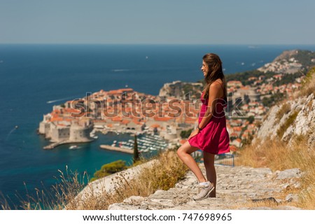 Woman-traveler having a good time visiting the city of Dubrovnik in Croatia. Picture taken from the mountain above Dubrovnik citadel, Croatia, Famous European Travel Destination.