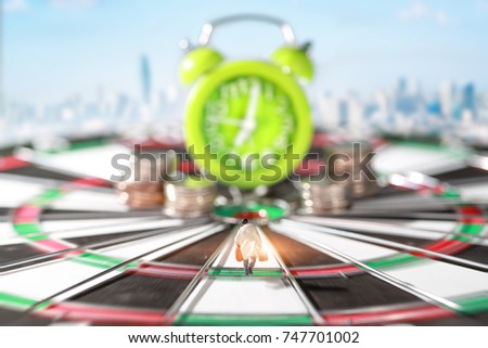 Miniature people: businessman running on dart board and try to race against time and beat the clock to be a winner with city image blur background (Financial and Business competition concept)
