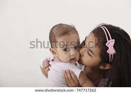 young girl holding her baby sister closely