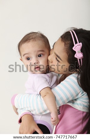 young girl holding and hugging baby