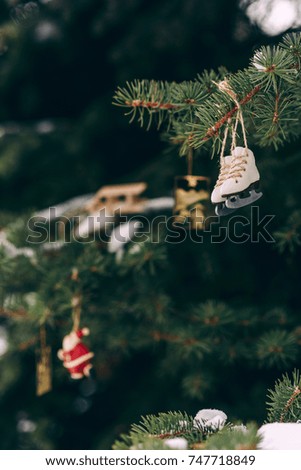 Closeup christmas tree decorations handmade miniature ice skates and other christmas toys on the snowy branch.