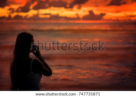 silhouette of a girl at sunset, speaks by mobile phone