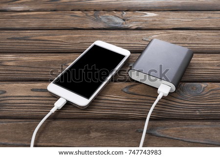 Powerbank charging smartphone - outdoor, wooden background
