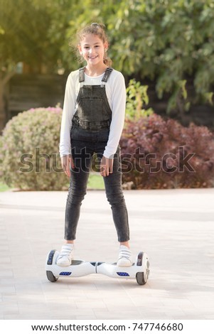 Teenager balancing on electric hover board personal eco transport.Child using popular electric transport a self-balancing, gyro scooter, smart balance wheel. A little girl riding a electric scooter .