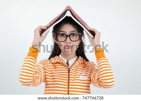 Education concept - Young attractive asian student in colorful t- shirt and blue jeans studying, reading,doing homework on white background. Red,blue yellow, green books and lovely focus serious girl.