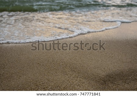 Artistic photo. Close-up on a wave withdrawing on the sand of a beach in the sunset