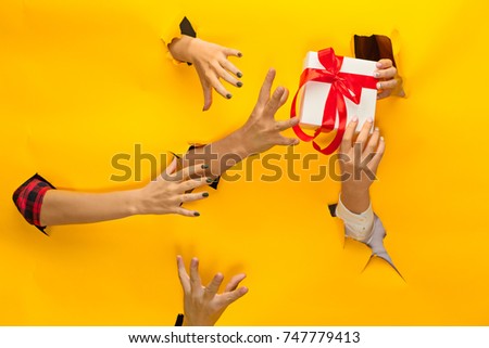 close-up of female hand holding a present through a torn paper, isolated