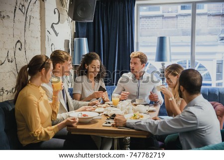 Group of friends are eating breakfast and socialising in a restaurant. 