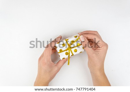 Woman holding small golden present box in hands on a white background.Flatly, top view
