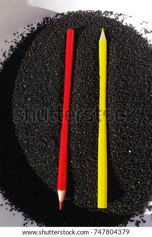 yellow and red pencils on black sand background